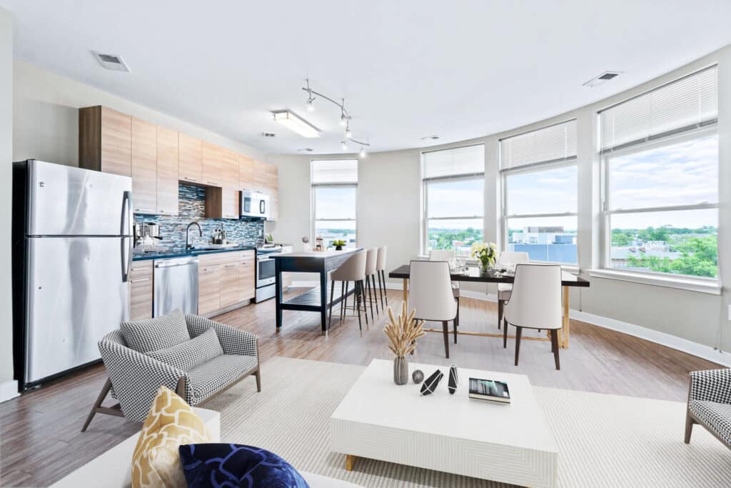 Open-plan modern apartment with a kitchen, dining area, and living space. Large windows provide ample natural light and offer a view of the outdoors.